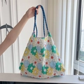Close-up of floral canvas tote bag with blue rope handle in a bright interior setting - Colorful Flowers