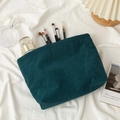 Dark green corduroy cosmetic bag showing spacious interior with skincare and brushes - Malachite green