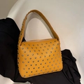 Yellow leather rivet shoulder bag with metal studs and top zipper on fabric background - Brown
