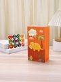 Orange cartoon dinosaur paper gift bag with matching round stickers for children's parties - Orange
