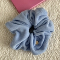 Close-up of light blue towel fabric headband with soft texture and golden metal tag - Scrunchie / Blue