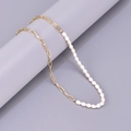 Gedetailleerd zicht op gouden paperclipketting en barokparels op een displaystandaard - 46cm Ketting / 46cm