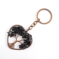 Macro shot of bronze Tree of Life pendant with black natural stones on a keyring - Obsidian
