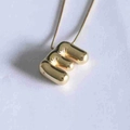 Detail of golden 3D balloon letter E pendant with polished mirror finish on snake chain - Letter E
