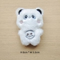 Detail view of 8x5.5cm white plush panda accessory with embroidery on wooden background - Full Body Panda