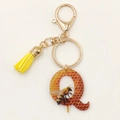 Detail of bee letter Q keychain with honeycomb pattern, yellow tassel and golden clasp - Letter Q