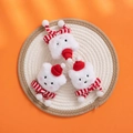 Three plush white kitten charms wearing red knitted hats and striped scarves on orange backdrop - Christmas Cat Head