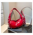 Détail d'un sac hobo rouge brillant avec clous argentés et reflet sur miroir métallique - Rouge