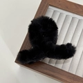 Detail view of a black faux fur hair claw clip on a wooden display tray with soft texture - Black