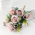 Detailed view of dusty pink silk roses in a paper bag with soft green foliage - Purple