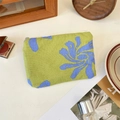 Florale grüne Münztasche mit blauen Mustern auf weißem Tisch mit Lifestyle-Deko - Grün