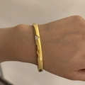 Macro shot of gold stainless steel bangle with a zircon-inlaid triangle charm detail - Triangle Diamond Style (A1172) / Gold