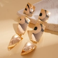 Dettaglio macro di orecchini geometrici placcati in oro 18k con design a torsione quadrata - Perno per orecchini in argento placcato oro vero / Oro