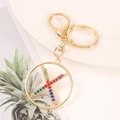 Detail of golden X-shaped letter keychain with multi-colored crystals and lobster clasp - Letter X