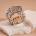 Dettaglio ravvicinato di un bracciale vintage argentato con stelle smaltate e gemme arancio - Giallo