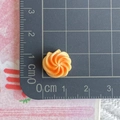 Close-up of a 1cm orange swirl resin miniature bread charm on a measurement cutting mat - Cream Cookie