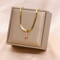 Dettaglio di una collana a serpente dorata con pendente rettangolare rosa su scatola - Collana / Rosa