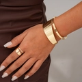Detailweergave van de glanzende gouden manchetarmband en bijpassende ring om de pols - Armband + Ring Set / Goud (Tweeledige set)