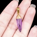 Natural amethyst bullet pendant with gold plating shown held by hand for scale - Amethyst