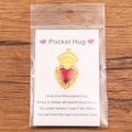 Pocket Hug gold finish red enamel heart pendant on a greeting card presentation - Gold Embrace Charm