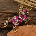 Vintage unicorn brooch with pink crystals and bronze base over a natural background - Pink Unicorn