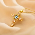 Nahaufnahme eines goldenen Kreuzanhängers mit bösem Blick und Zirkonia auf Seide - Orange