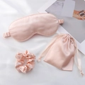 Light pink satin sleep set with eye mask, drawstring bag, and hair scrunchie on fabric - Flesh Pink