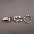 Détail macro du clip foulard vintage argenté avec nœud infini sur fond de cuir texturé - Style 32 (Clip de porte-clés nœud d'infinité en argent)