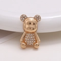 Detail of golden bear charm with inlaid rhinestones on a clean white surface - Gold Bear