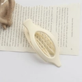 Minimalist beige oval duckbill hair clip placed on a book page for styling - Frosted White