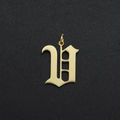 Macro shot of a golden gothic letter U charm with polished finish and circular bail - Letter V