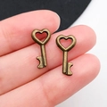 Ciondoli a forma di cuore in bronzo vintage mostrati sulle dita per la misura - Chiave Piccola in Bronzo Antico 8x15mm