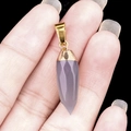 Amethyst hexagonal bullet stone pendant with golden metal clasp held in hand - Grey Agate