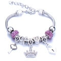 Detail of silver charm bracelet featuring pink crystals, heart key, and crown pendants - Purple