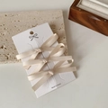Detailed view of beige silk bow hair clips set on a display card for elegant styling - Set of 3 / Off-white - 3pcs