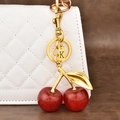 Golden cherry keychain with glitter red cherries and letter K tag on a handbag - Letter K