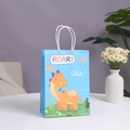 Blue dinosaur paper gift bag with white rope handles and ROAR typography on a table - Blue Dinosaur (Roar)
