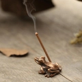 Vue macro d'un porte-encens grenouille en bronze antique sur un fond Zen en bois - Grenouille