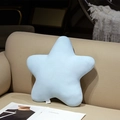 Coussin peluche étoile bleu clair doux posé sur un canapé beige avec magazine - Étoile bleue