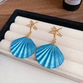 Détail de boucles d'oreilles étoile de mer dorée et coquillage bleu sur plateau velours - 33# Tige d'oreille en acier - Bleu