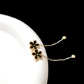 Detail of black enamel flower earring with gold chain and bead on white ceramic tray - Black Gold Flower Chain (Single)