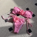 Flat lay of pink 2-piece bikini featuring 3D rose appliqués and side-tie bottoms - Pink