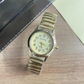 Detail of quartz watch with gold stretch band and pale yellow dial on wood background - Women's Watch / Gold Steel Strap Gold Dial