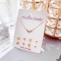 Detalle de conjunto de collar de corazón dorado y pendientes de lazo sobre cartón - Tarjeta Blanca-Collar de Corazón Dorado y 4 Pares de Pendientes (Lazo/Corazón de Perla/Conejo/Corazón Pequeño)