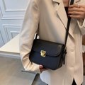 Classic black leather crossbody bag with a square gold clasp shown on a model - Black