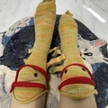 Detail of funny knit crocodile socks with orange and green stripes and button eyes - Chameleon