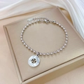 Detail of silver bead bracelet with coin-style hollow pendant on champagne jewelry box - Silver