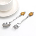 Mini metal spoon and fork set with vintage amber gemstone handles on white background - Topaz