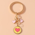 Macro view of gold keychain with pink heart charms and round yellow enamel pendant - Yellow-Pink