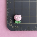 Detailed view of a mini pink resin peach charm with green leaves on a measuring mat - Pink Flower